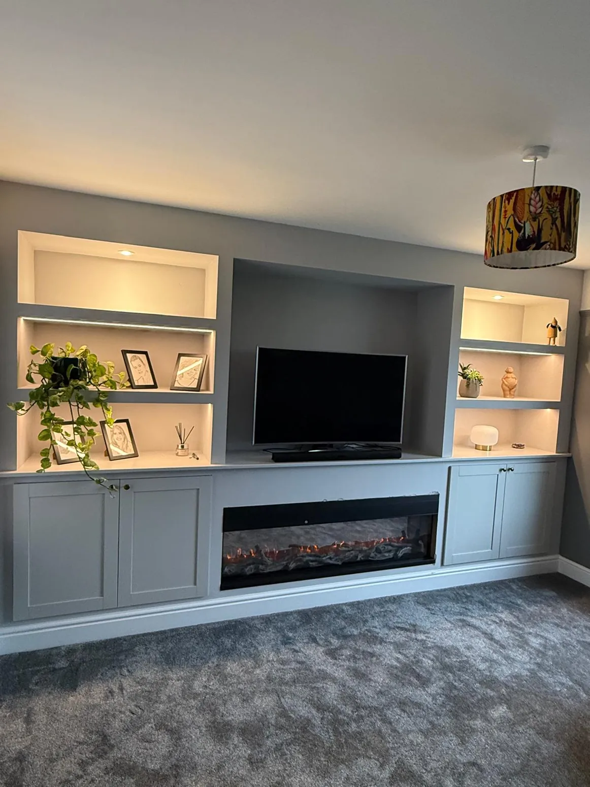 Blue-grey built-in media wall with illuminated display shelving