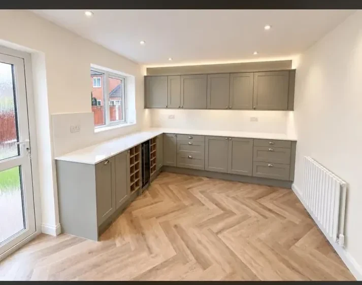 Neutral shaker-style kitchen with pale units and herringbone flooring