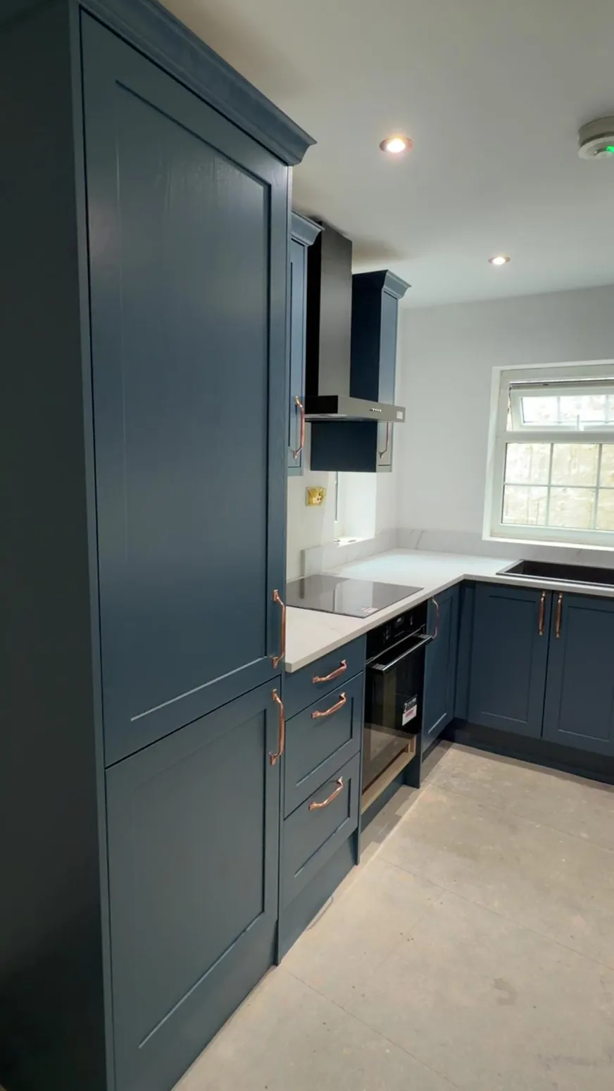 Deep blue bespoke fitted kitchen cabinetry and white worktop