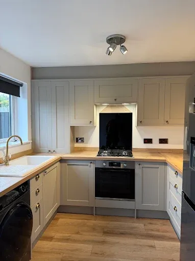 Light-coloured shaker-style kitchen and natural timber worktops