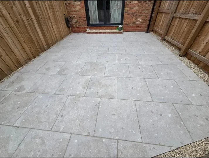 Clean porcelain paving alongside house and garden fencing