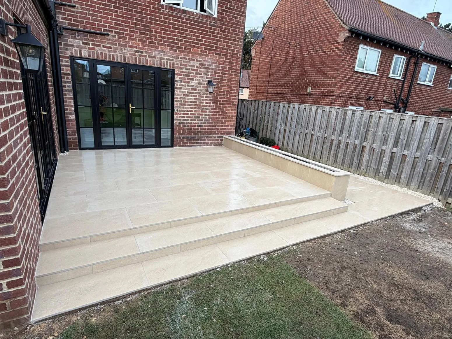 Large cream porcelain patio and steps outside brick house
