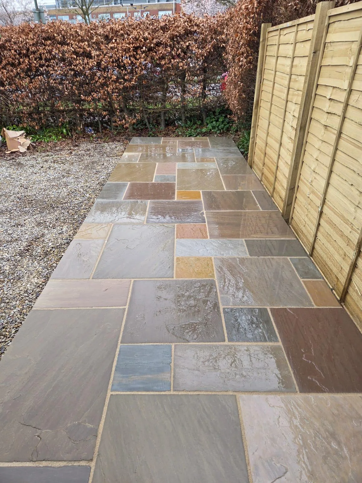 Multicolour stone pathway and patio beside fencing