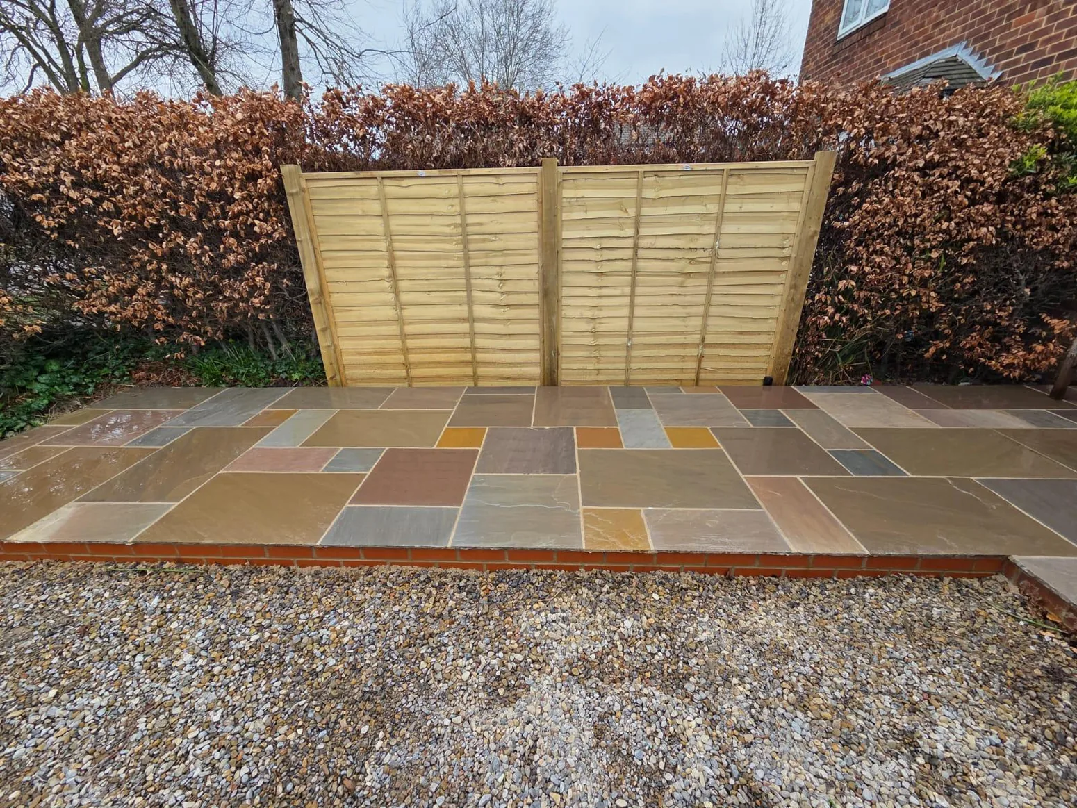 Small raised Indian stone patio area with new fence
