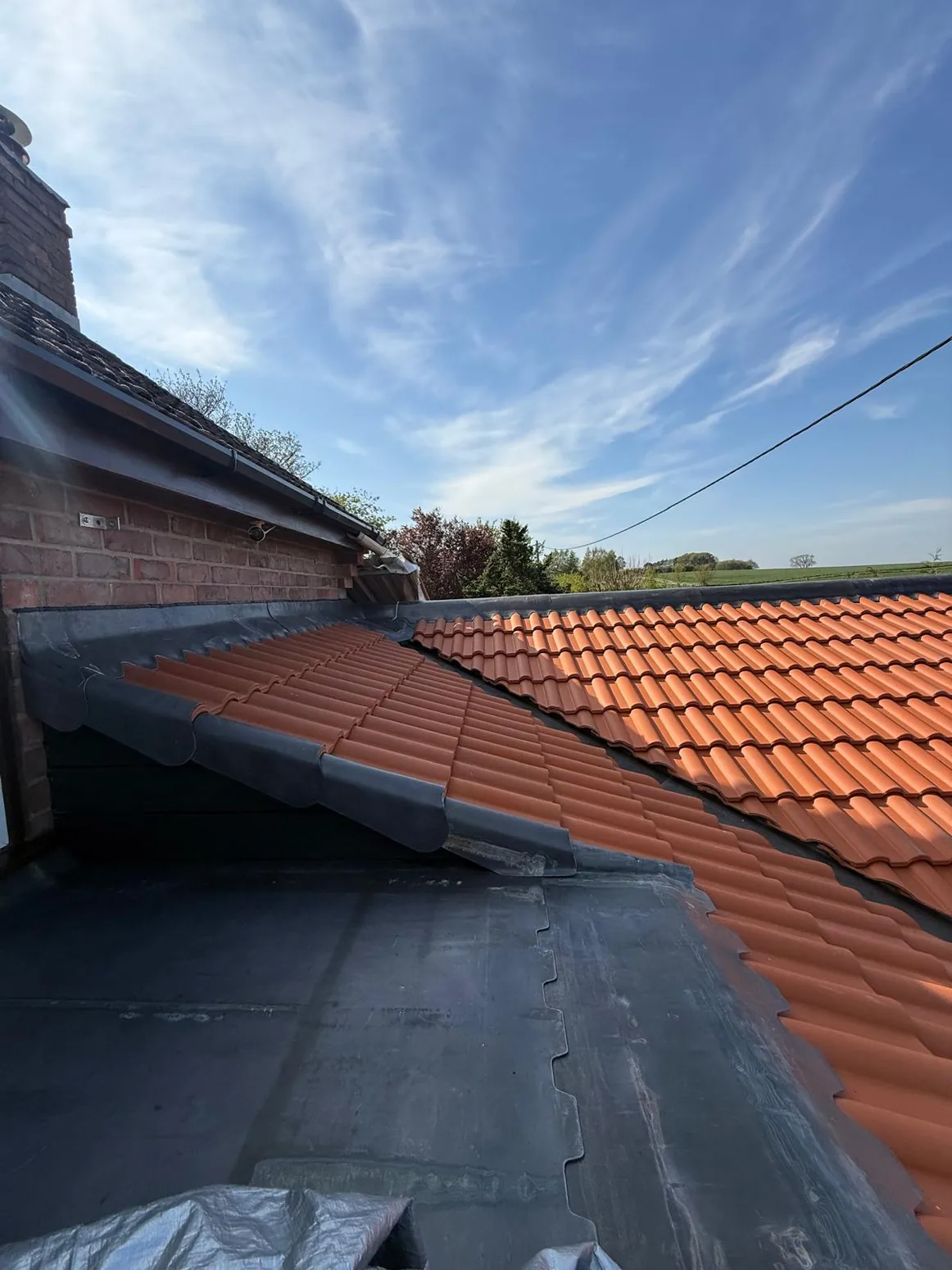Neat roof tile installation against adjoining pitched roof